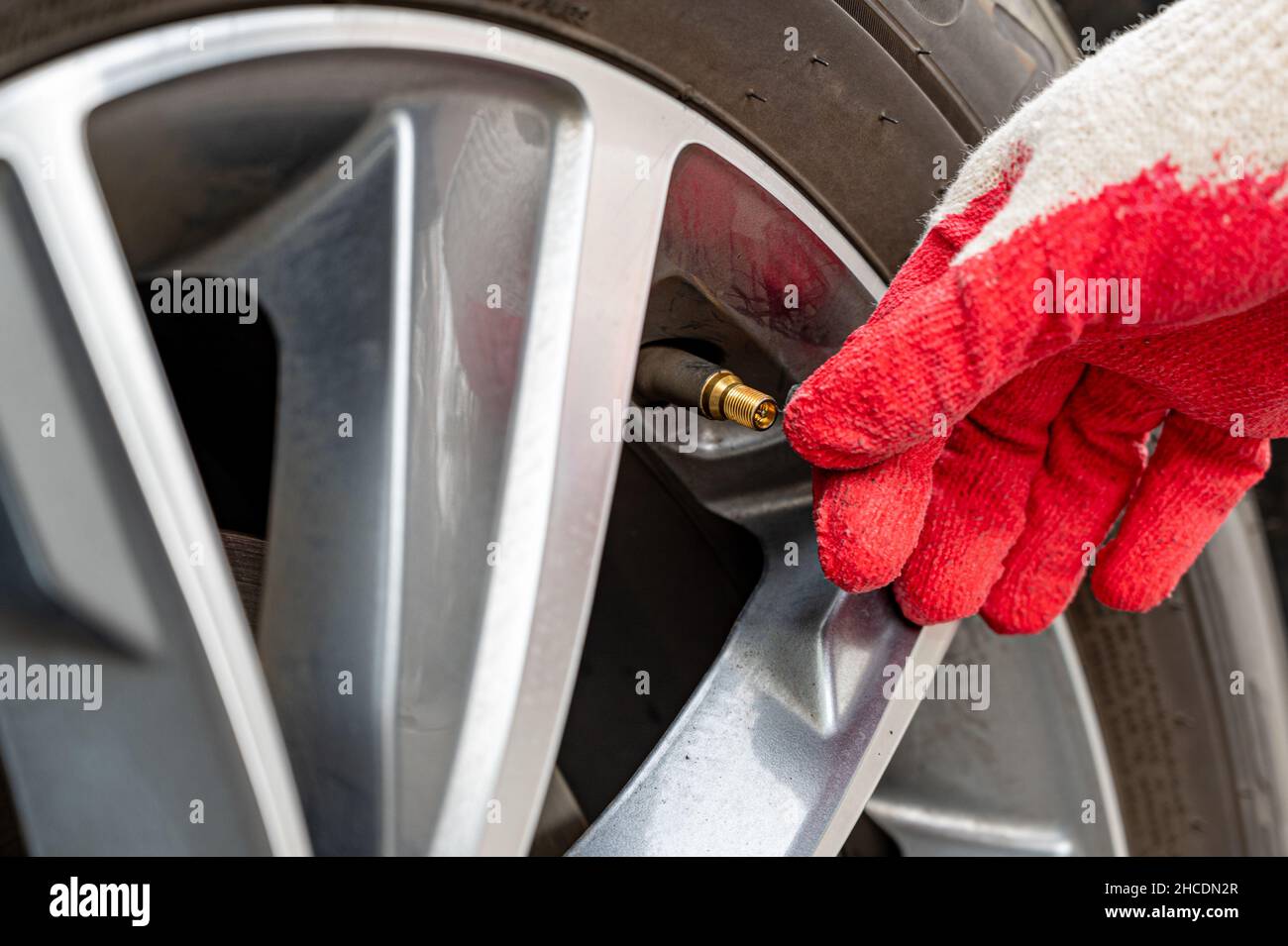 Uomo che riempie l'aria nello pneumatico. Controllo della pressione dell'aria da parte del conducente dell'auto. Foto Stock