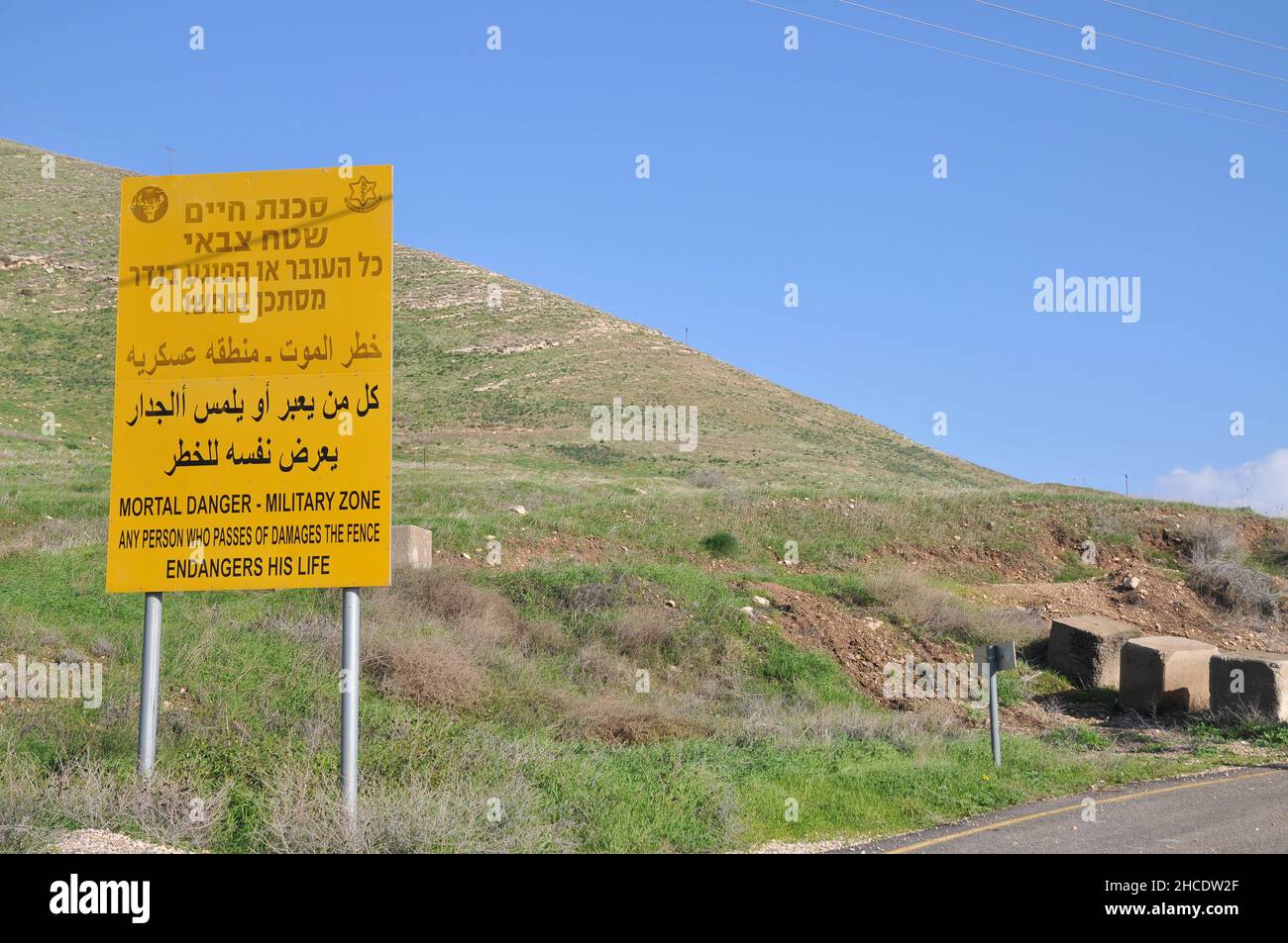 Israele, Golan. Il siriano frontiera israeliana recintare un simbolo giallo di avvertimento come visto dal lato Israeliano Foto Stock