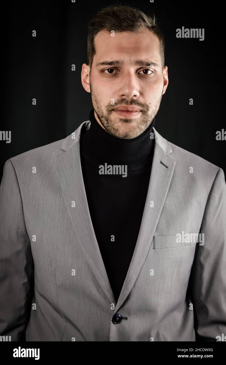 ritratto di un giovane uomo d'affari in abito grigio e dolcevita nero, guardando serio, da vicino Foto Stock