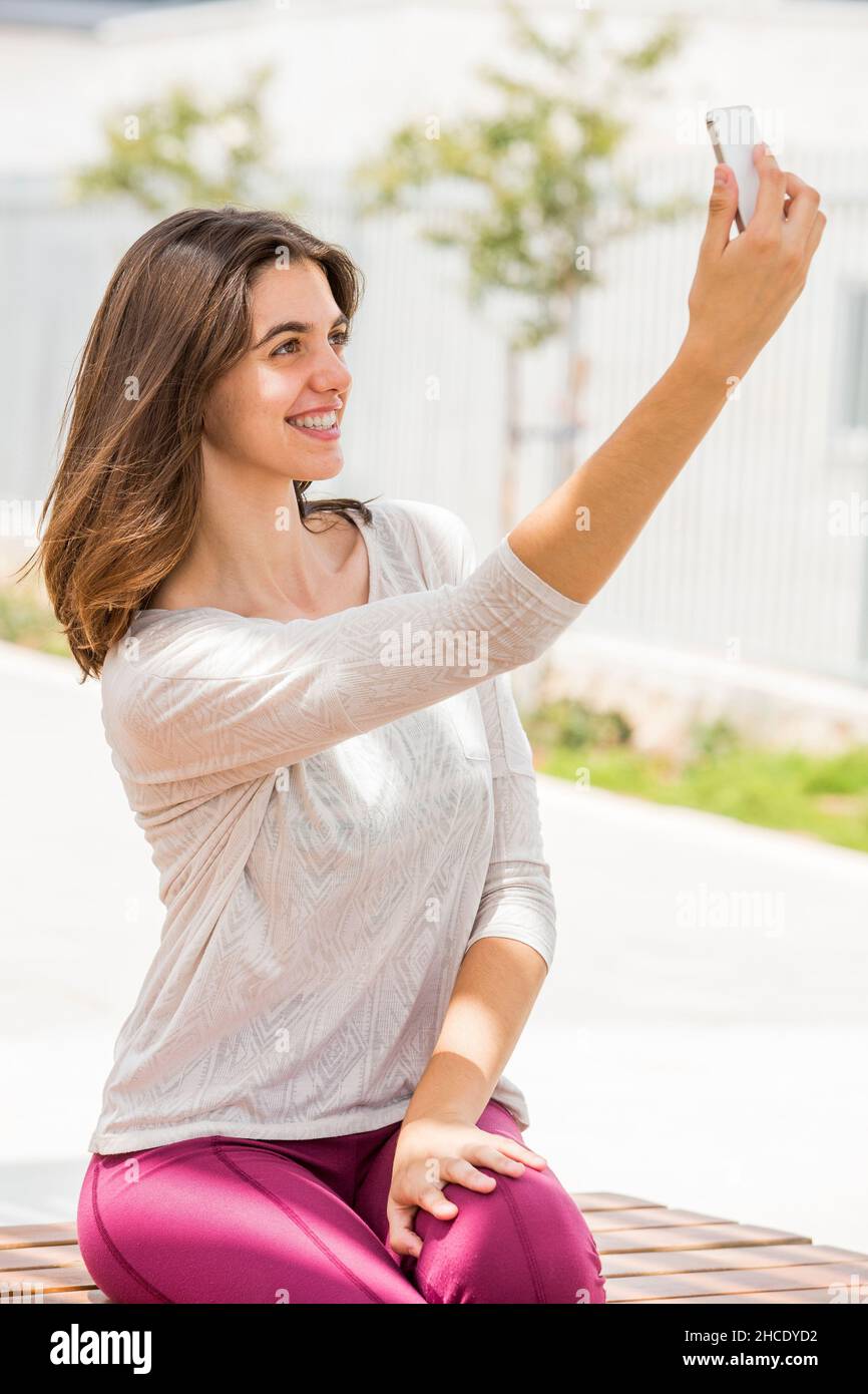 Giovane donna in abbigliamento sportivo casual porta un selfie fuori Foto Stock