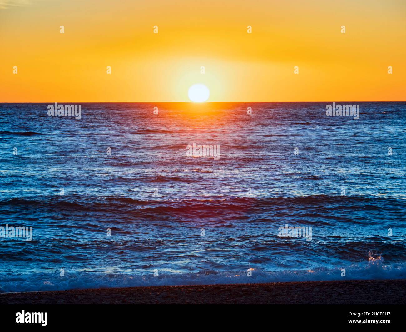 Il sole tramonta su una tranquilla serata di mare Foto Stock