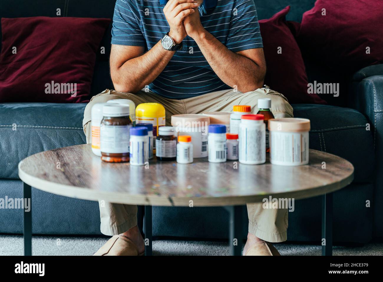 Concetto di persona malata con farmaci medici. Combattere la malattia con medicinali. Uomo preoccupato con bottiglie Medicine sul tavolo. Foto Stock