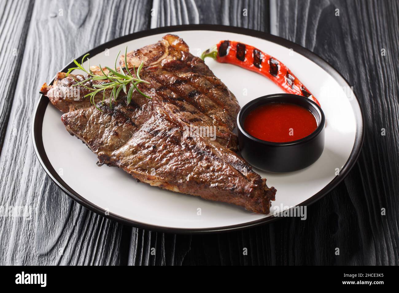 Gourmet Grill Restaurant Steak Menu T-Bone Beef Steak primo piano nel piatto sul tavolo nero. Orizzontale Foto Stock