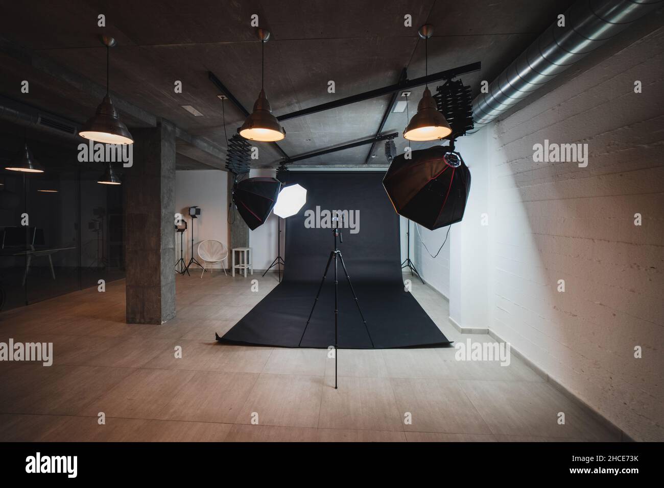 Interno di moderno studio fotografico con octabossi e fotocamera professionale su treppiede su sfondo nero Foto Stock
