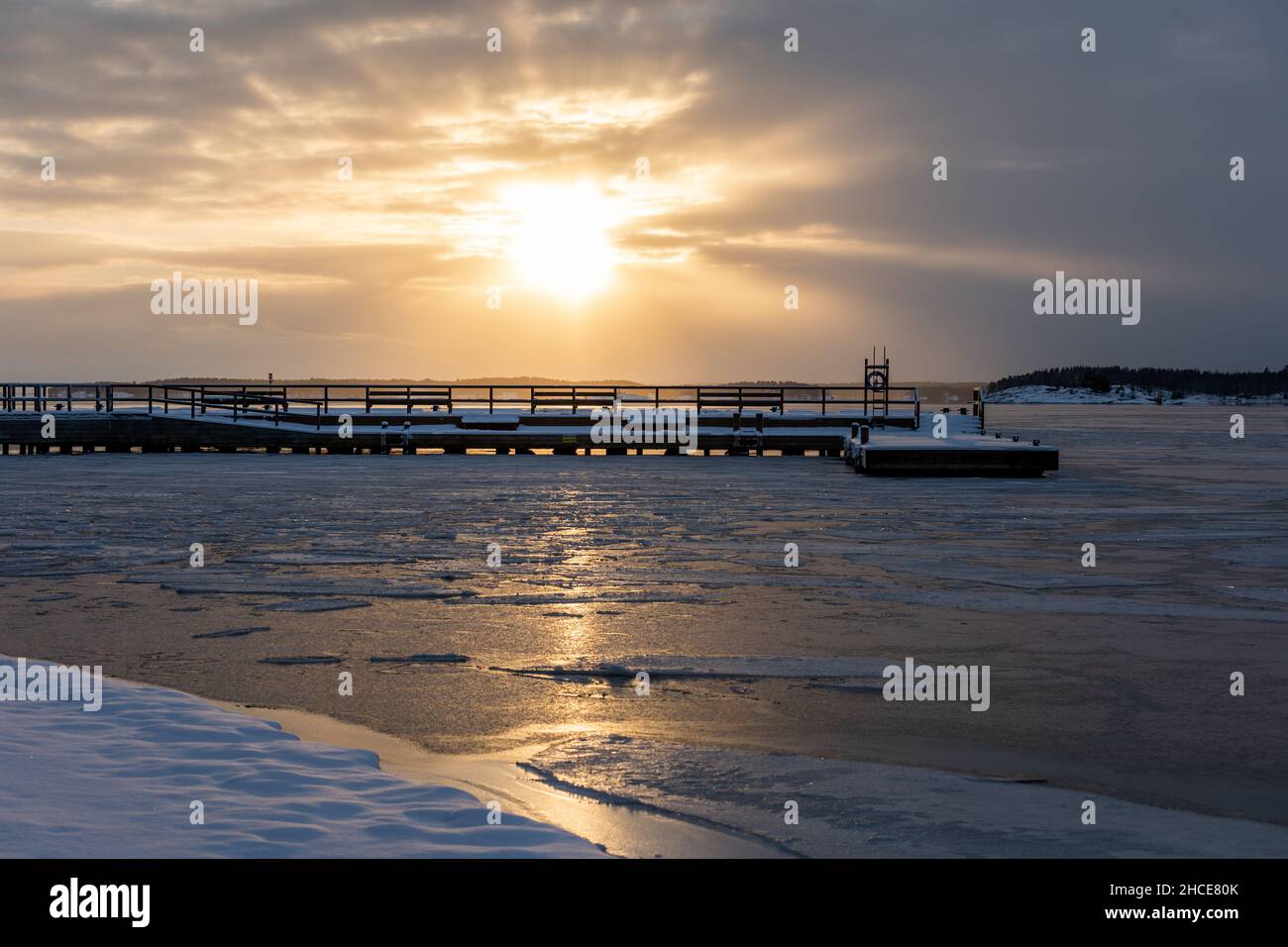 Bellissimo tramonto dietro un molo in mare ghiacciato a Ruissalo, Turku, Finlandia. Foto Stock