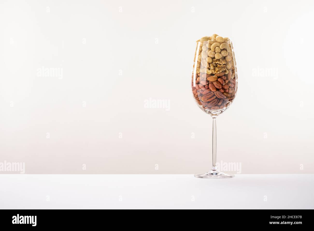 Vaso di vetro riempito con una varietà di nutrizione e snack sani e noci su uno sfondo bianco Foto Stock