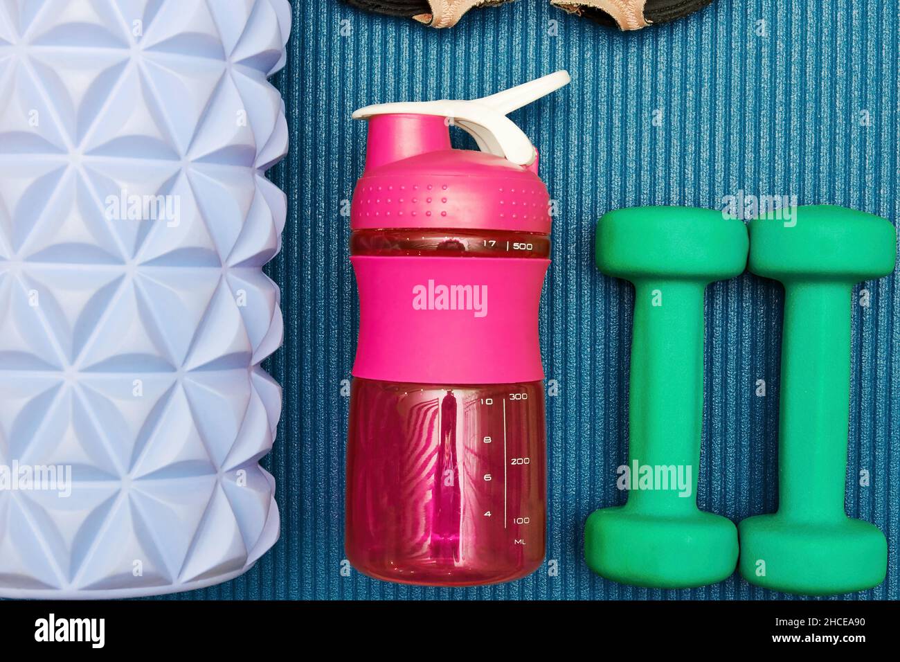 Modello flatlay con attrezzature sportive, manubri, rullo, bottiglia d'acqua sul materassino fitness. Sport e stili di vita sani background e concetti Foto Stock