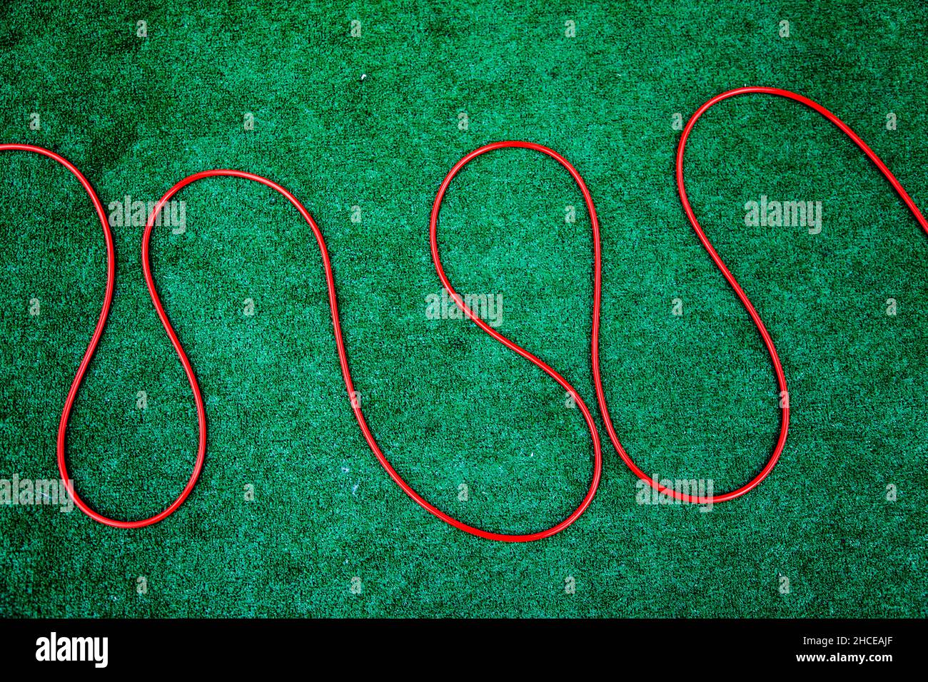 Tubo flessibile rosso sull'erba sintetica verde Foto Stock