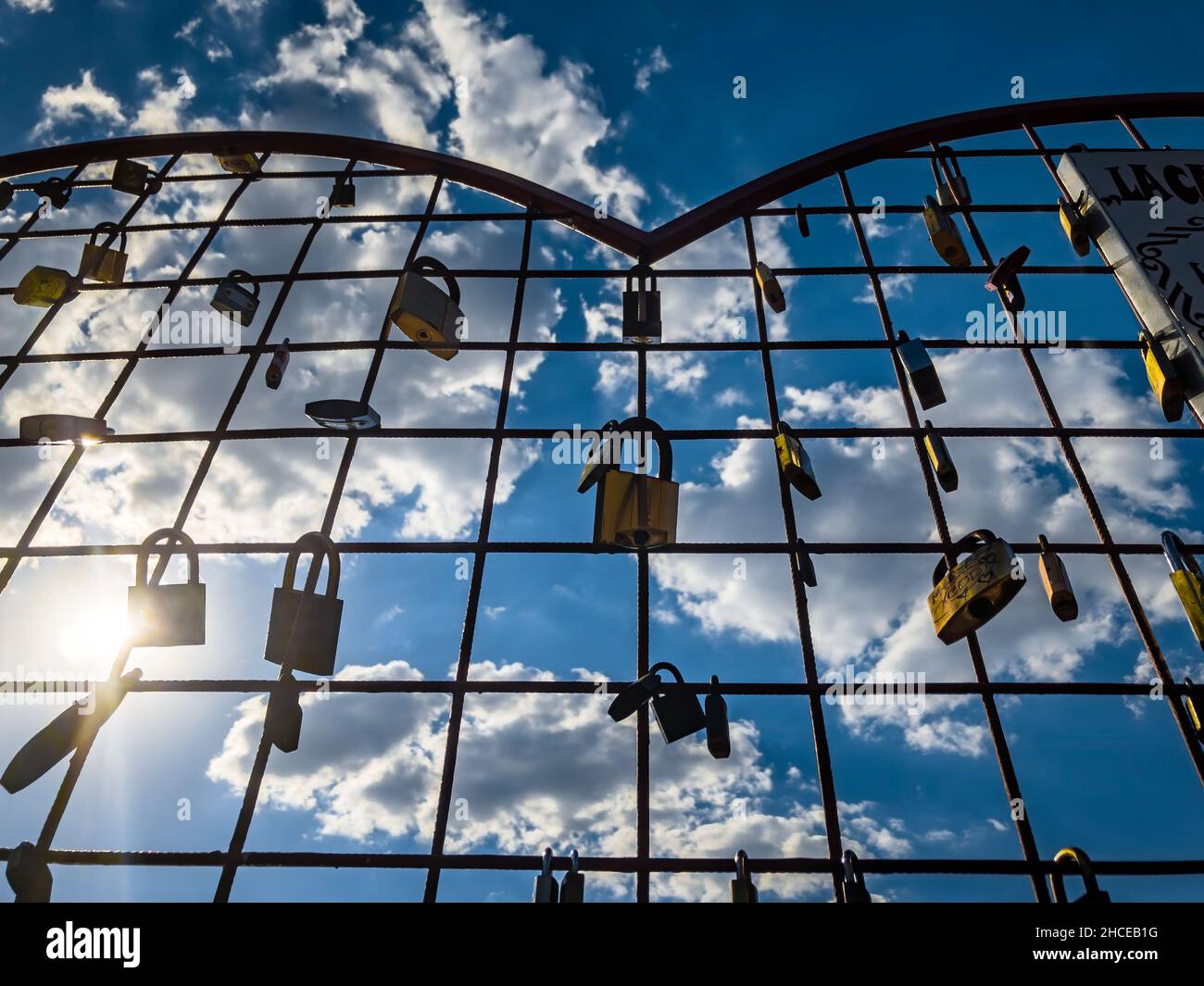 Scatto ad angolo basso di una recinzione a forma di cuore con lucchetti su sfondo cielo nuvoloso Foto Stock