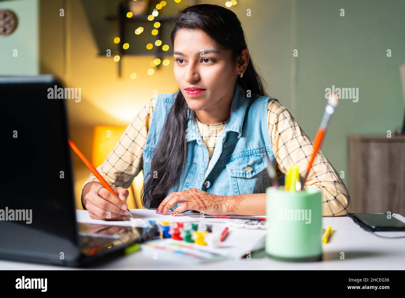 Giovani donne indiane che imparano la pittura dalla classe in linea osservando nel laptop - concetto di formazione virtuale in linea, videochiamata, Internet e. Foto Stock