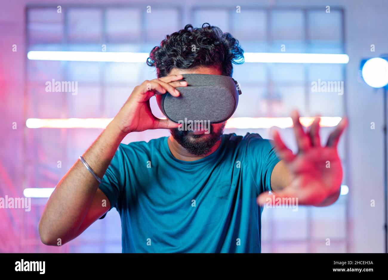 i giovani gamer professionisti si divertano giocando a un'esperienza di gioco realistica con vr o visore per realtà virtuale su sfondo neon chiaro - concetto di moderno Foto Stock