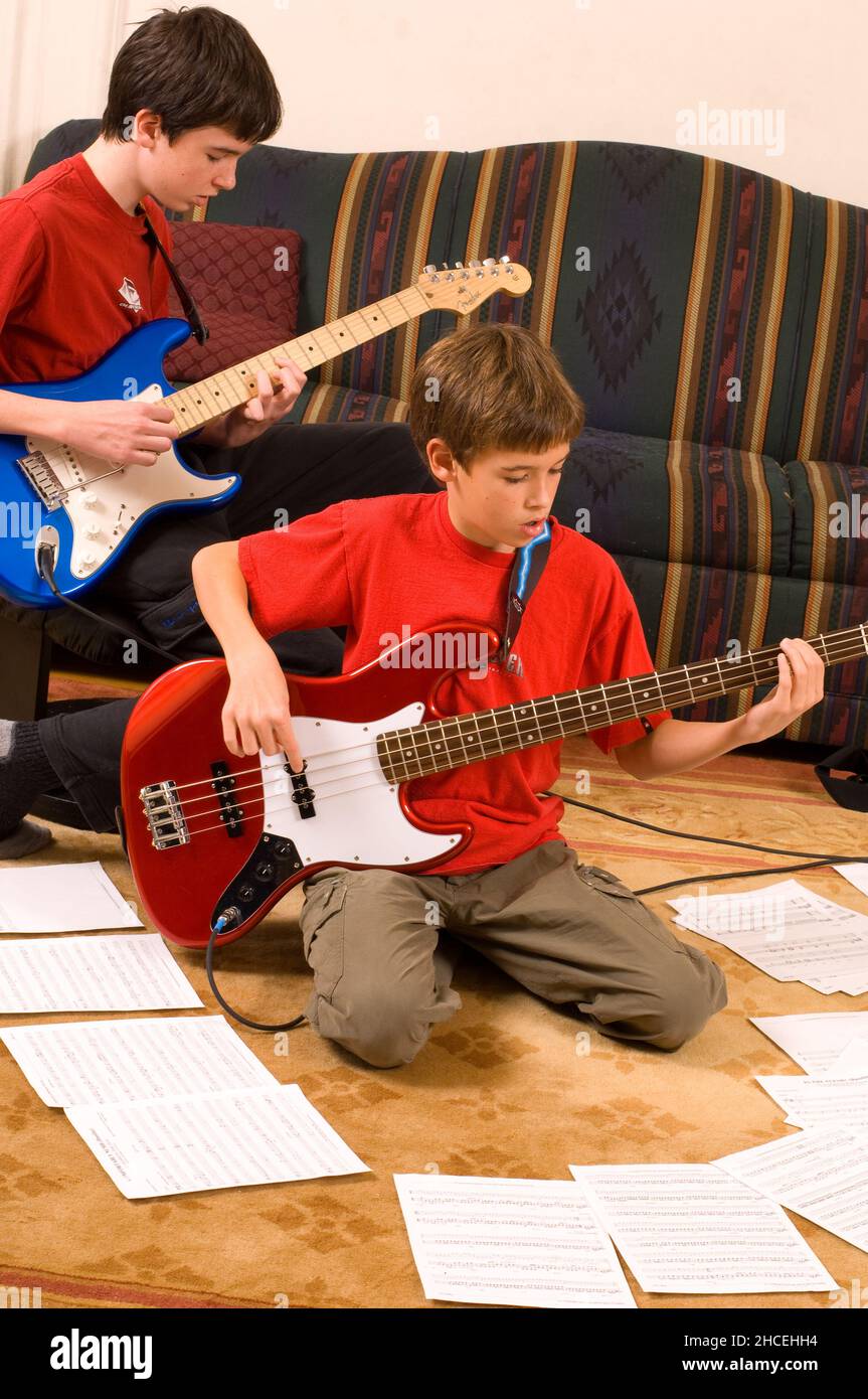 ragazzo di 13 anni a casa suonando la chitarra elettrica, suonando con il fratello di 12 anni Foto Stock
