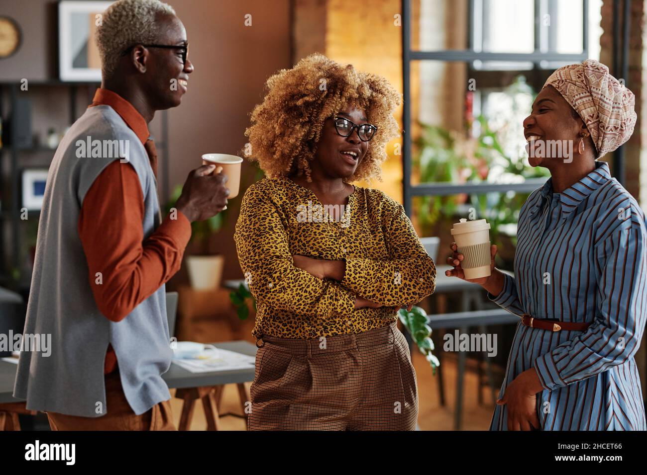 Gli uomini d'affari africani parlano tra loro e bevono caffè durante la pausa caffè in ufficio Foto Stock