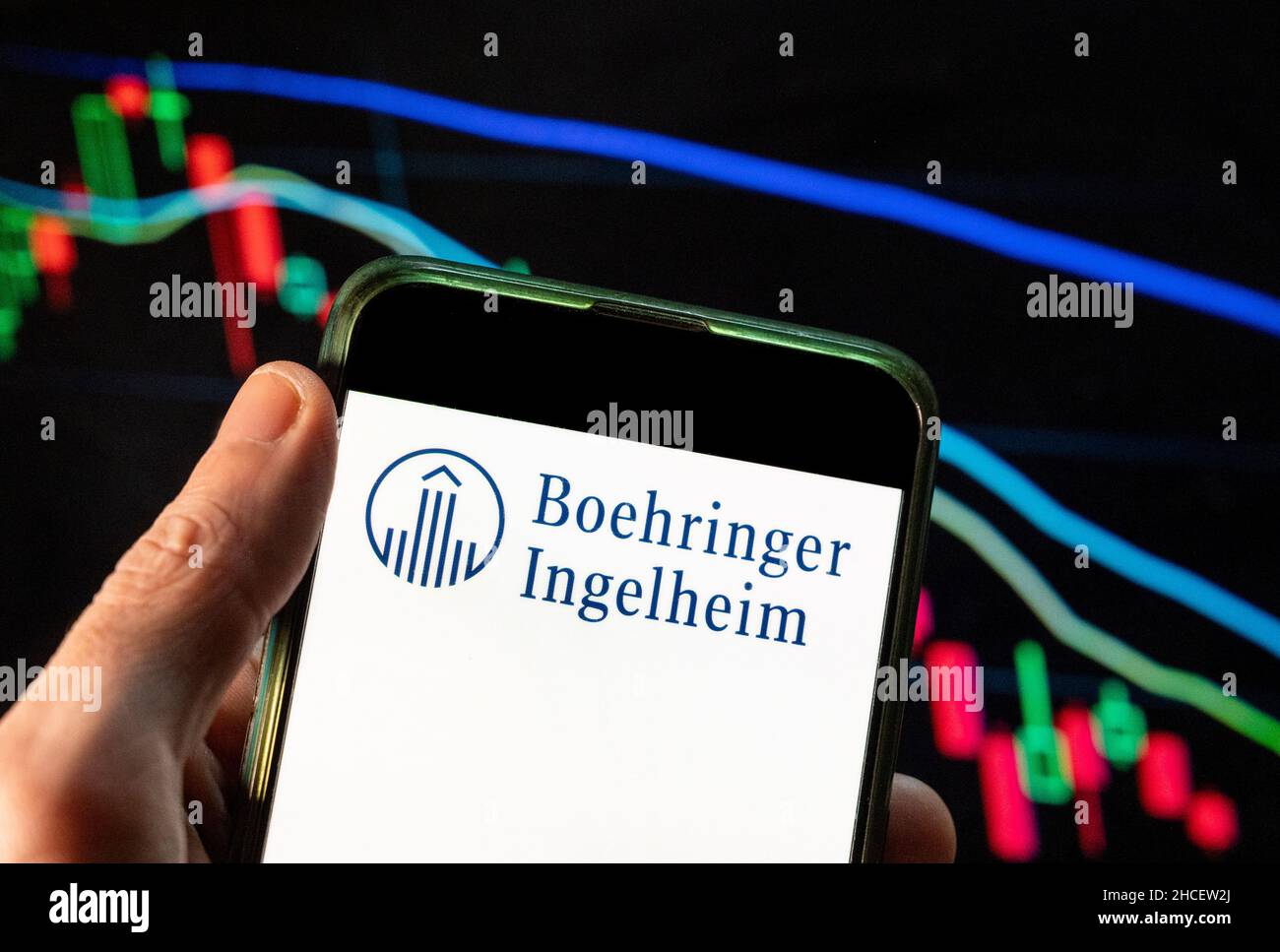 In questa foto è illustrato il logo della società farmaceutica tedesca Boehringer Ingelheim, un'azienda farmaceutica guidata dalla ricerca, visualizzato su uno smartphone con un grafico dell'indice delle borse economiche sullo sfondo. Foto Stock