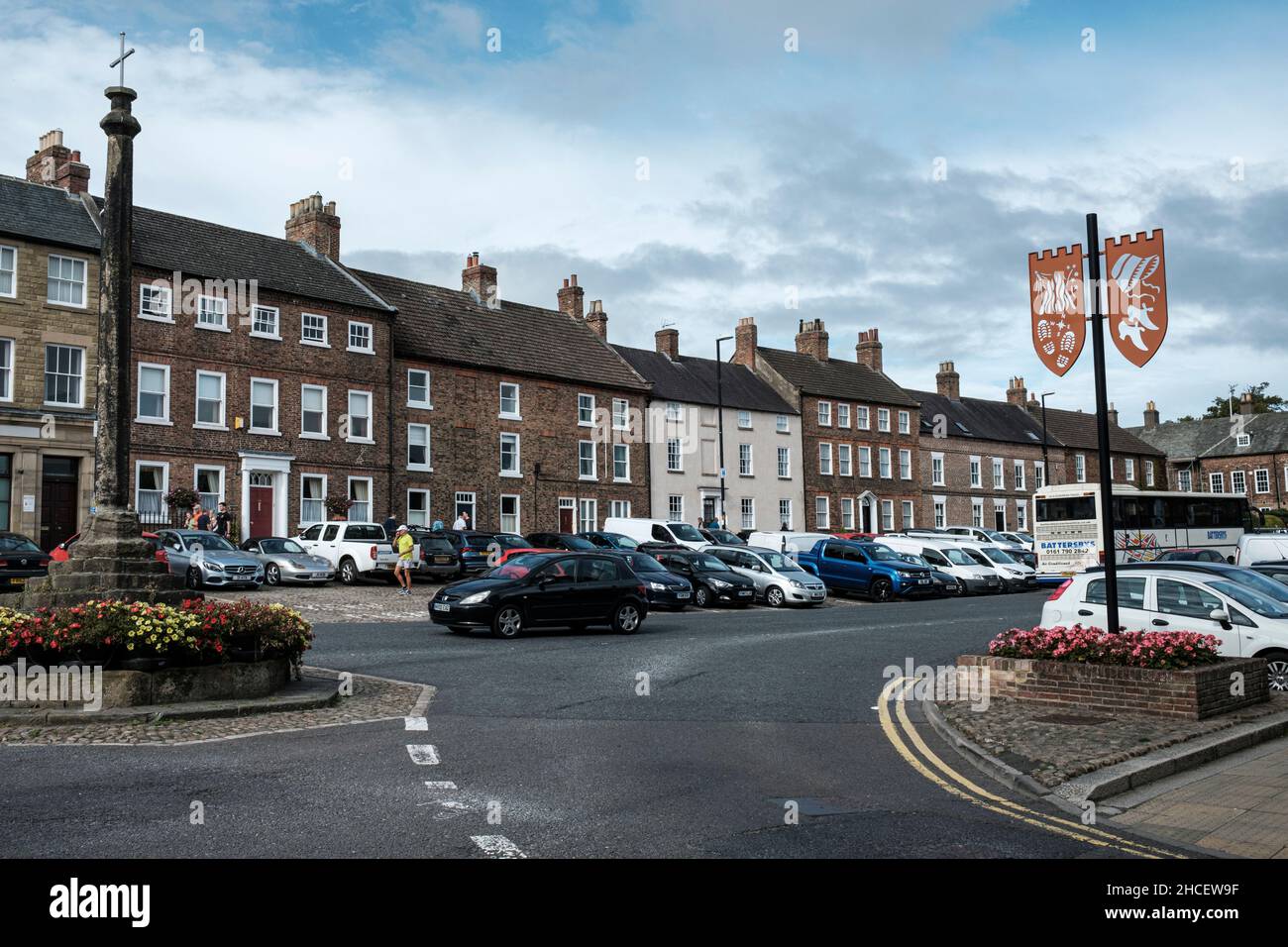 Bedale High Street con la croce del mercato e scudi decorativi, North Yorkshire, Inghilterra Foto Stock