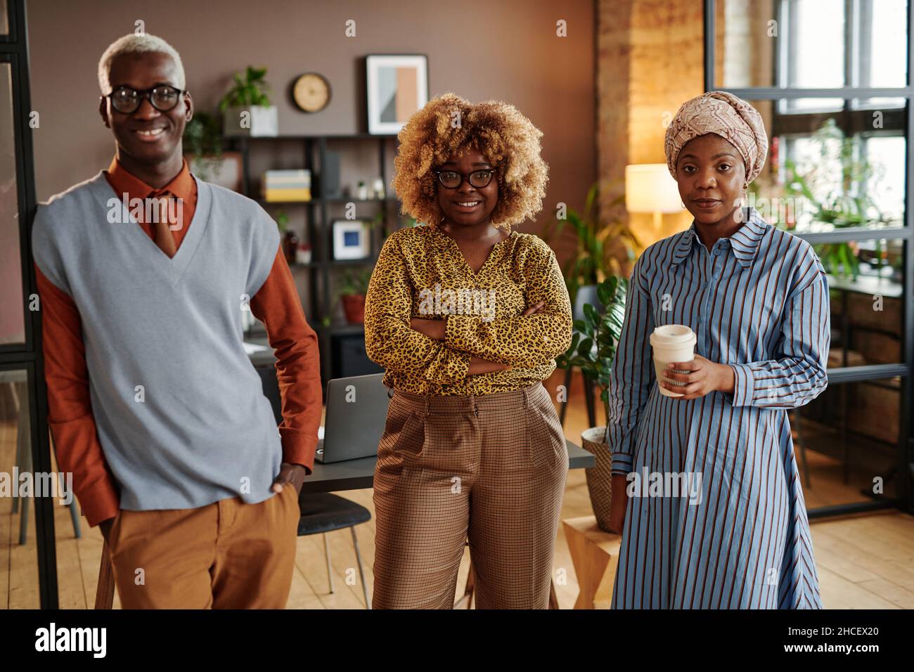 Ritratto di persone africane di successo che sorridono alla macchina fotografica mentre si levano in piedi insieme in ufficio Foto Stock