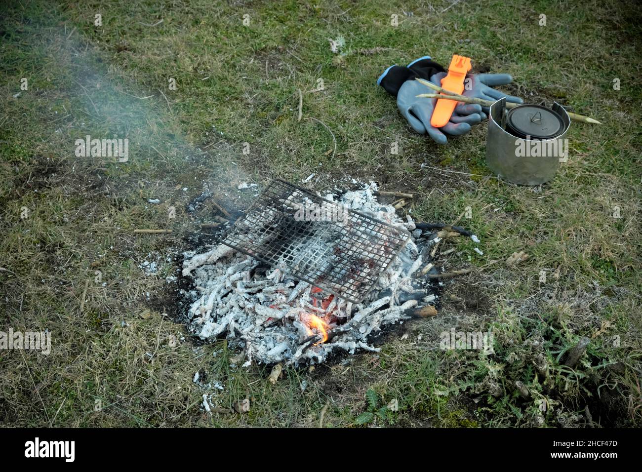 attività di campeggio selvaggio in attività ricreative all'aperto una piccola griglia sulle braci di fuoco campo e altre attrezzature Foto Stock