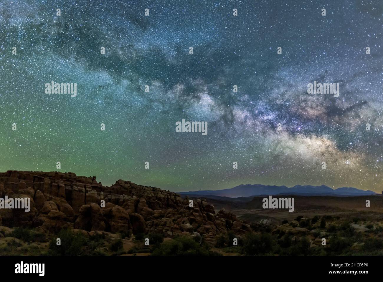 Una Via lattiginosa blu-verde brillante e verde bagliore d'aria sulle pinne di roccia rossa della fornace Fiery nell'Arches National Park, Moab, Utah. Foto Stock