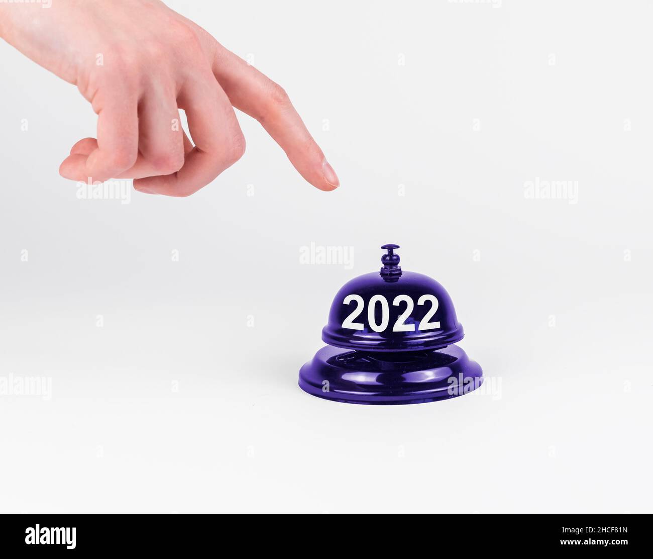 Concetto di inizio anno nuovo 2022. Premere il pulsante del campanello sulla scrivania con un dito. Foto Stock