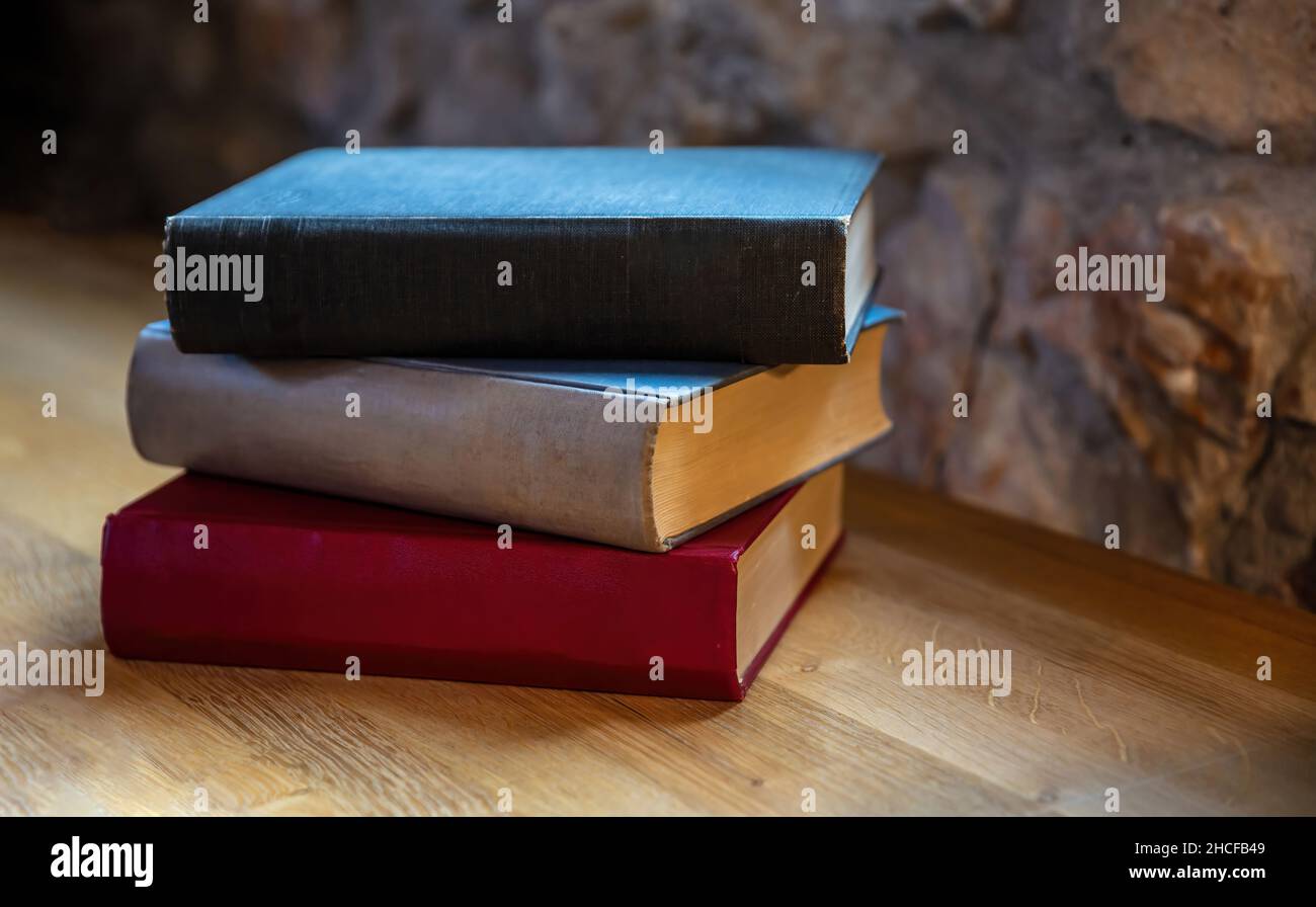 I libri si impilano su un tavolo. Vecchi taccuini chiusi su sfondo della scrivania in legno, vista da primo piano. Ufficio legale, scrivania per studenti Foto Stock