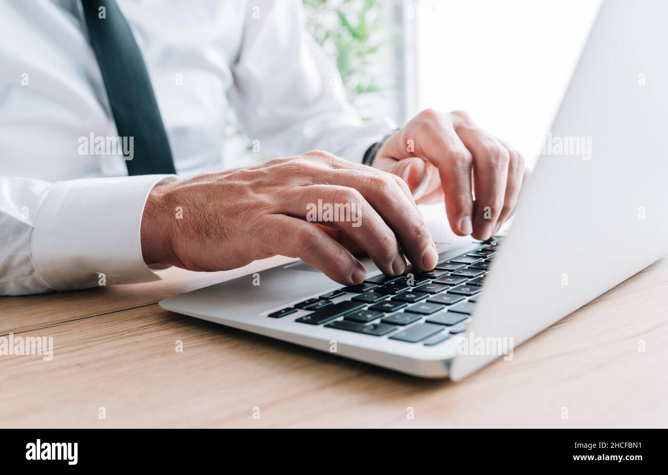 Colletto bianco che il lavoratore digita computer portatile tastiera alla scrivania, fuoco selettivo Foto Stock