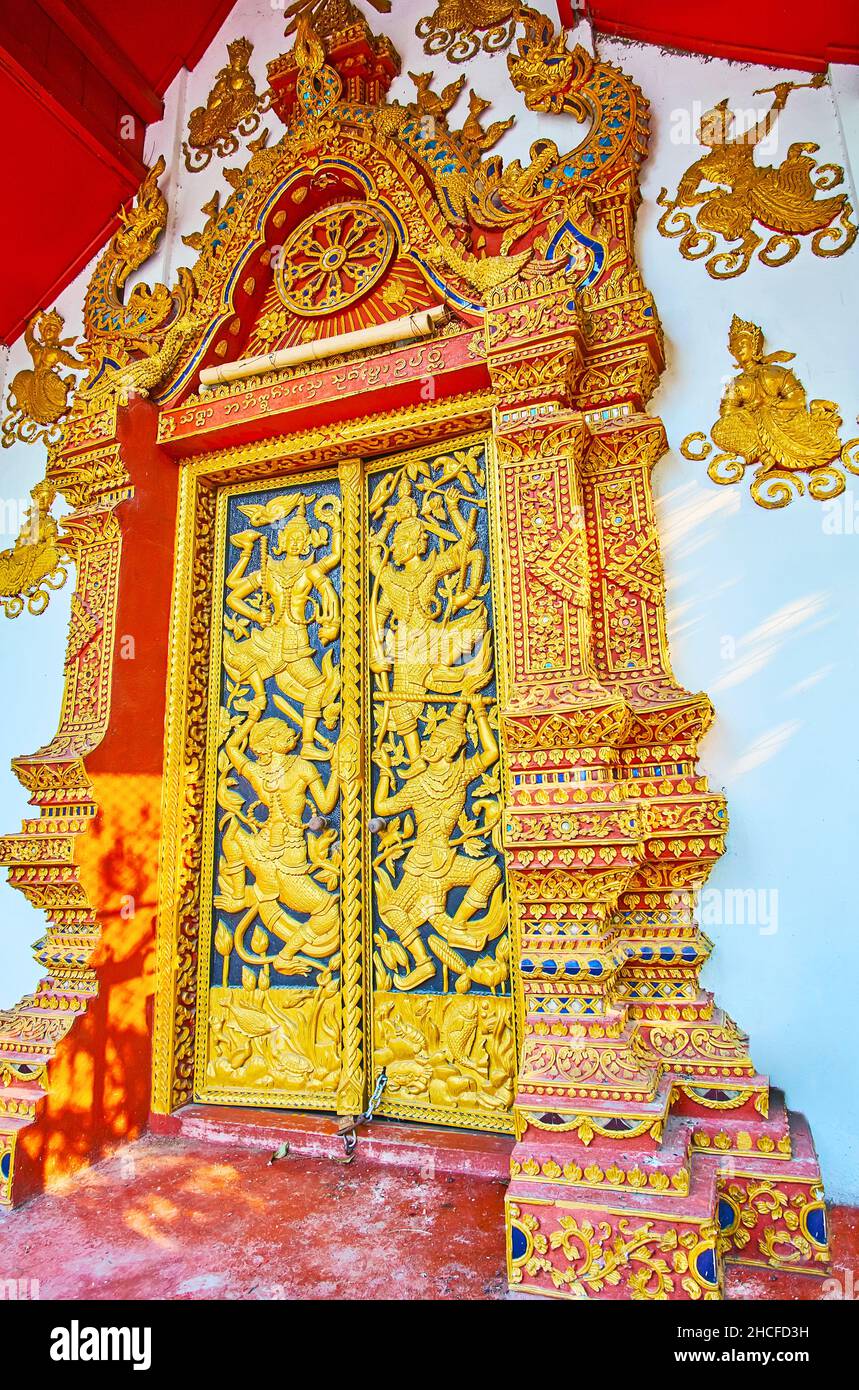 La porta ornata di Wat mai Tang (Wat Methang) Ubosot, decorata con scultura dorata della scena di combattimento con Yakshas, Chiang mai, Thailandia Foto Stock