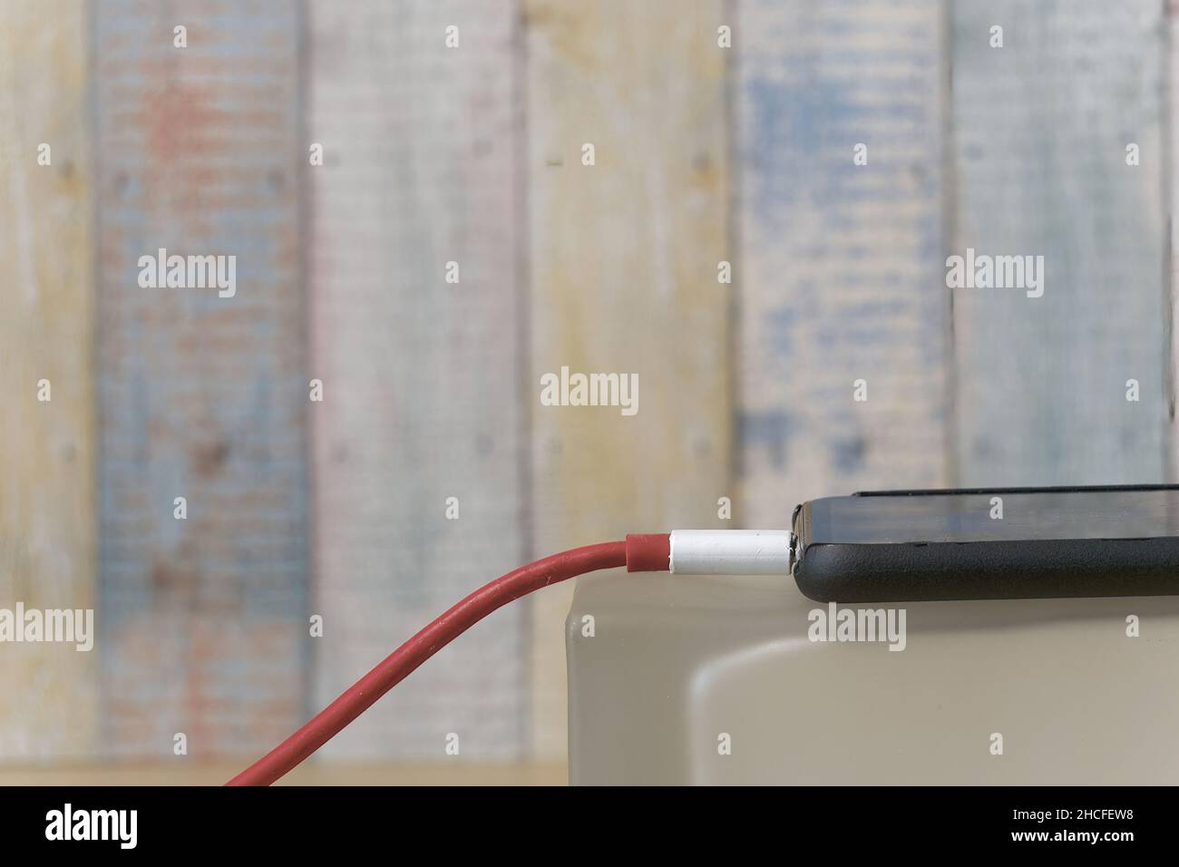 Primo piano di uno smartphone collegato a un caricabatterie con uno sfondo sfocato Foto Stock