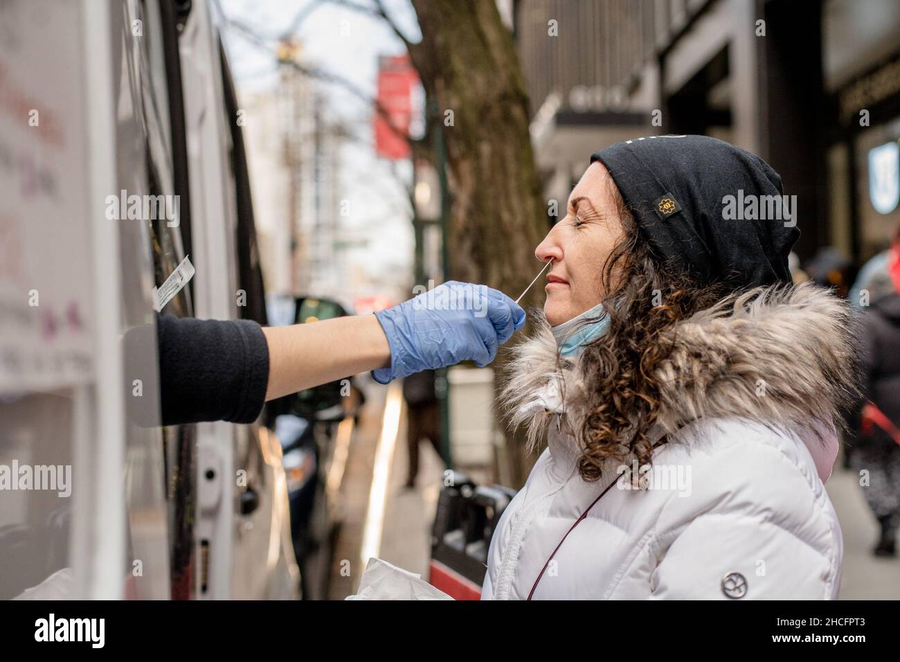 New York, Stati Uniti. 27th Dic 2021. Un operatore sanitario raccoglie un campione di tampone da una persona per il test COVID-19 presso un sito di test COVID-19 mobile nel centro di Manhattan. Gli ambulatori mobili di prova offrono la PCR libera ed il test rapido dell'antigene ai residenti ed ai visitatori. Credit: SOPA Images Limited/Alamy Live News Foto Stock