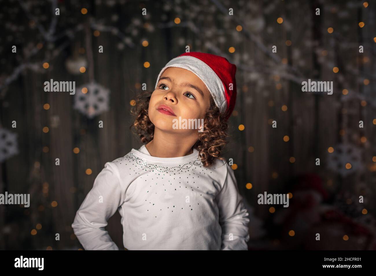 Adorabile ragazza spagnola con un cappello rosso durante un evento di Natale Foto Stock