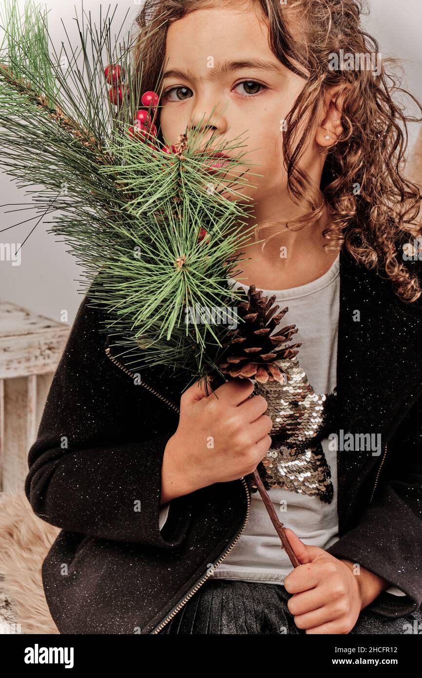 Adorabile ragazza spagnola che tiene un ramo di abete durante un evento di Natale Foto Stock