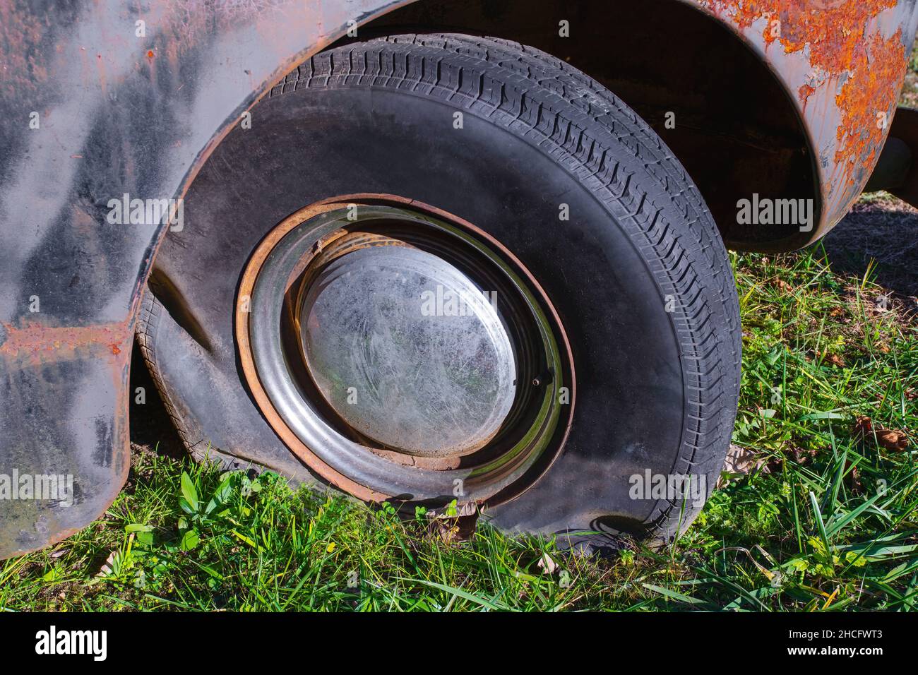 Pneumatico sgonfio su un vecchio veicolo arrugginito Foto Stock