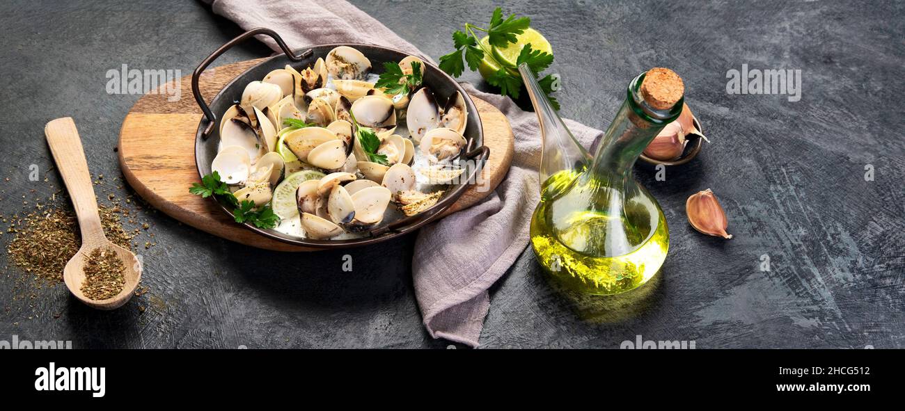 Venere vangole su sfondo grigio. Cucina tradizionale mediterranea. Panorama Foto Stock