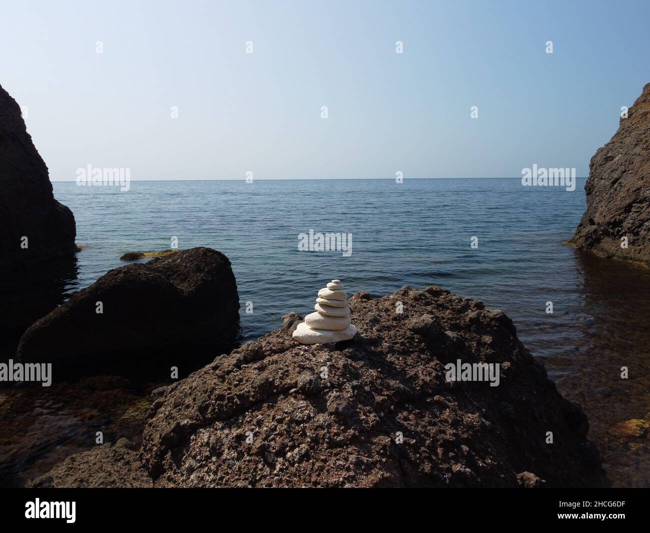 Piramide di ciottoli bilanciata sulla spiaggia nelle giornate di sole e cielo limpido al tramonto. Il mare d'oro bokeh sullo sfondo. Fuoco selettivo, pietre zen sulla spiaggia di mare Foto Stock