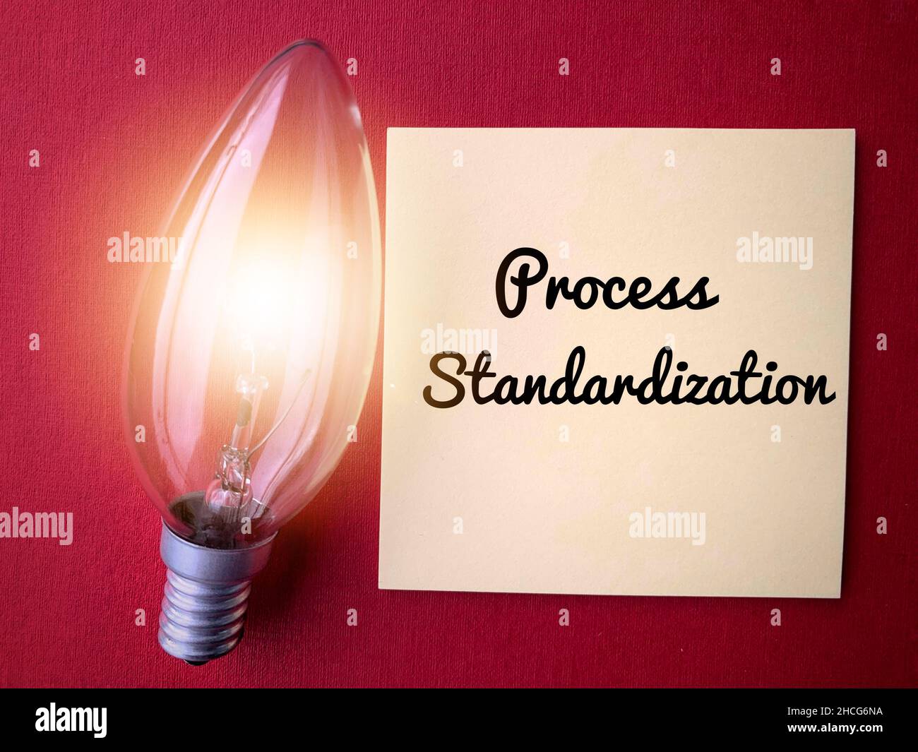 Standardizzazione del processo scritta su una nota adesiva con lampadina a sgranatura. Concetto e idee di business Foto Stock