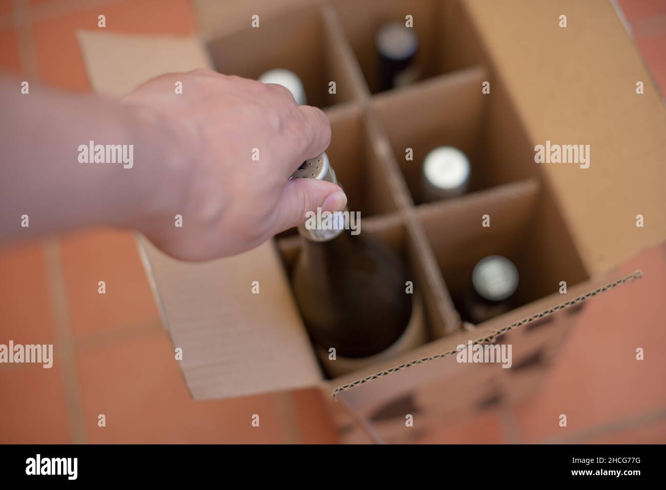 Persona che prende la bottiglia di vino fuori dalla scatola Foto Stock
