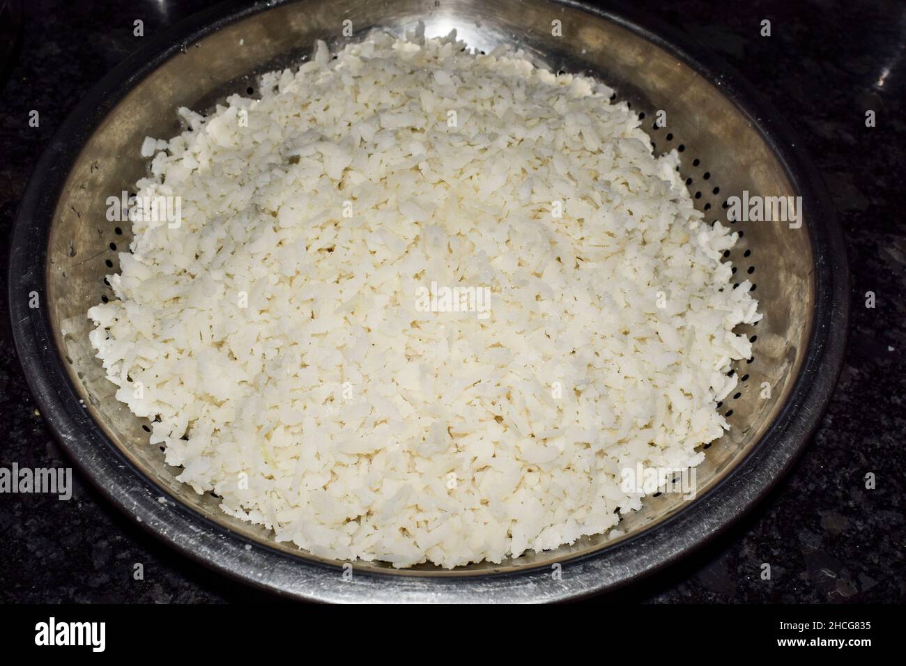 Cumuli di riso schiacciato imbevuto per la cottura del piatto maharastriano di POHA. Il riso bianco battuto è immerso in acqua pronto per la preparazione della colazione indiana d Foto Stock