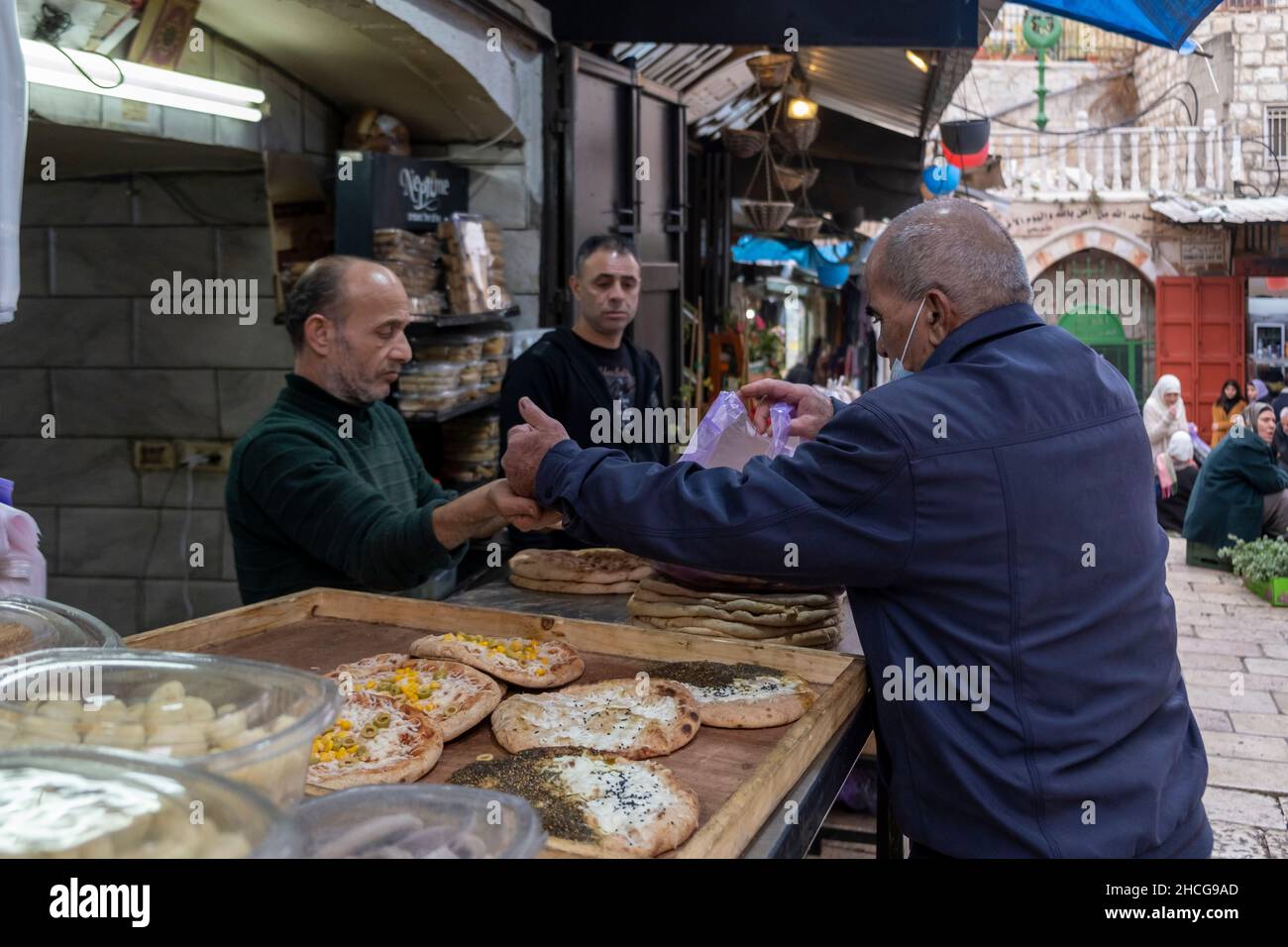 Un uomo palestinese compra il pane di Pita in via al wad che gli israeliani chiamano Haggai nel quartiere musulmano, città vecchia di Gerusalemme Israele Foto Stock