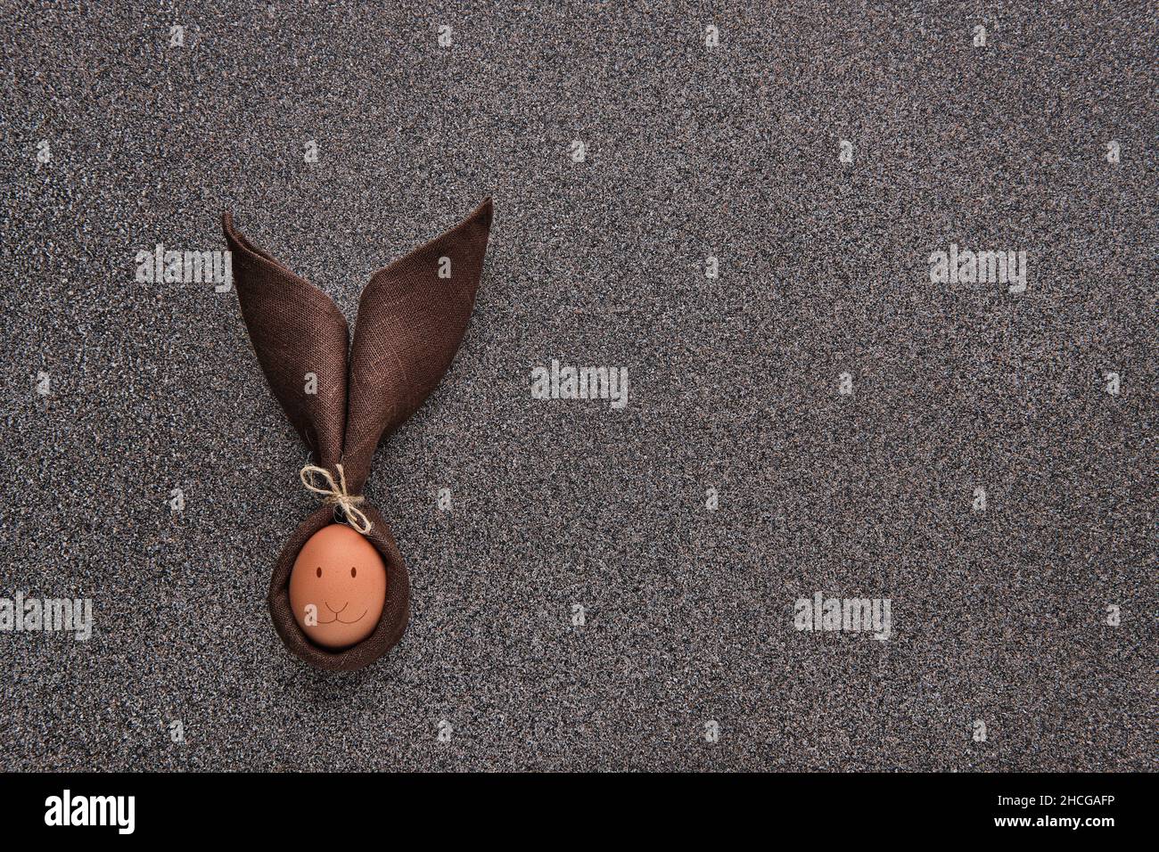 Concetto regalo di Pasqua - uovo avvolto in forma di coniglietto su sfondo di pietra scura Foto Stock