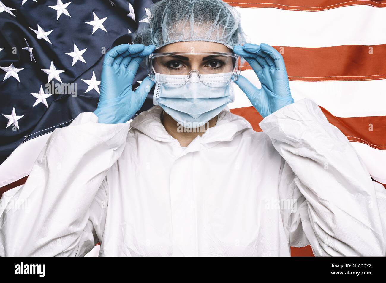 Medico o infermiere che indossa dispositivi di protezione personale medico (DPI) contro la bandiera americana Banner. Foto Stock