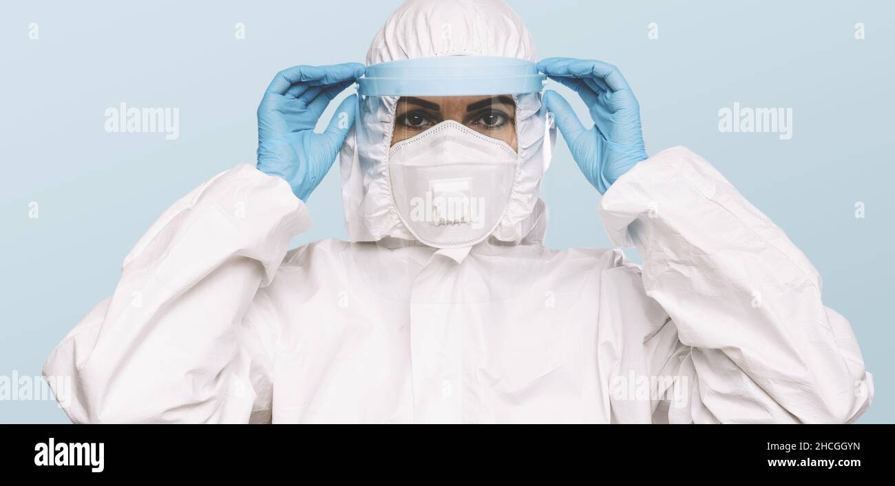 Medico o infermiere donna che indossa guanti protettivi in lattice e maschera protettiva medica con schermo e occhiali sul viso. Protezione per Coronavirus COVID-1 Foto Stock