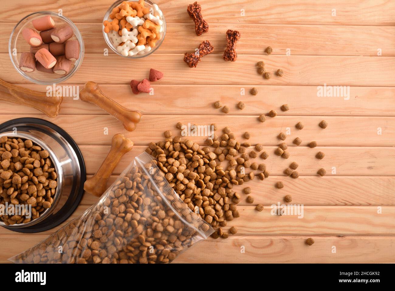 Sfondo con vari tipi di cibo secco per alimentare il cane su tavola di legno. Vista dall'alto. Composizione orizzontale. Foto Stock