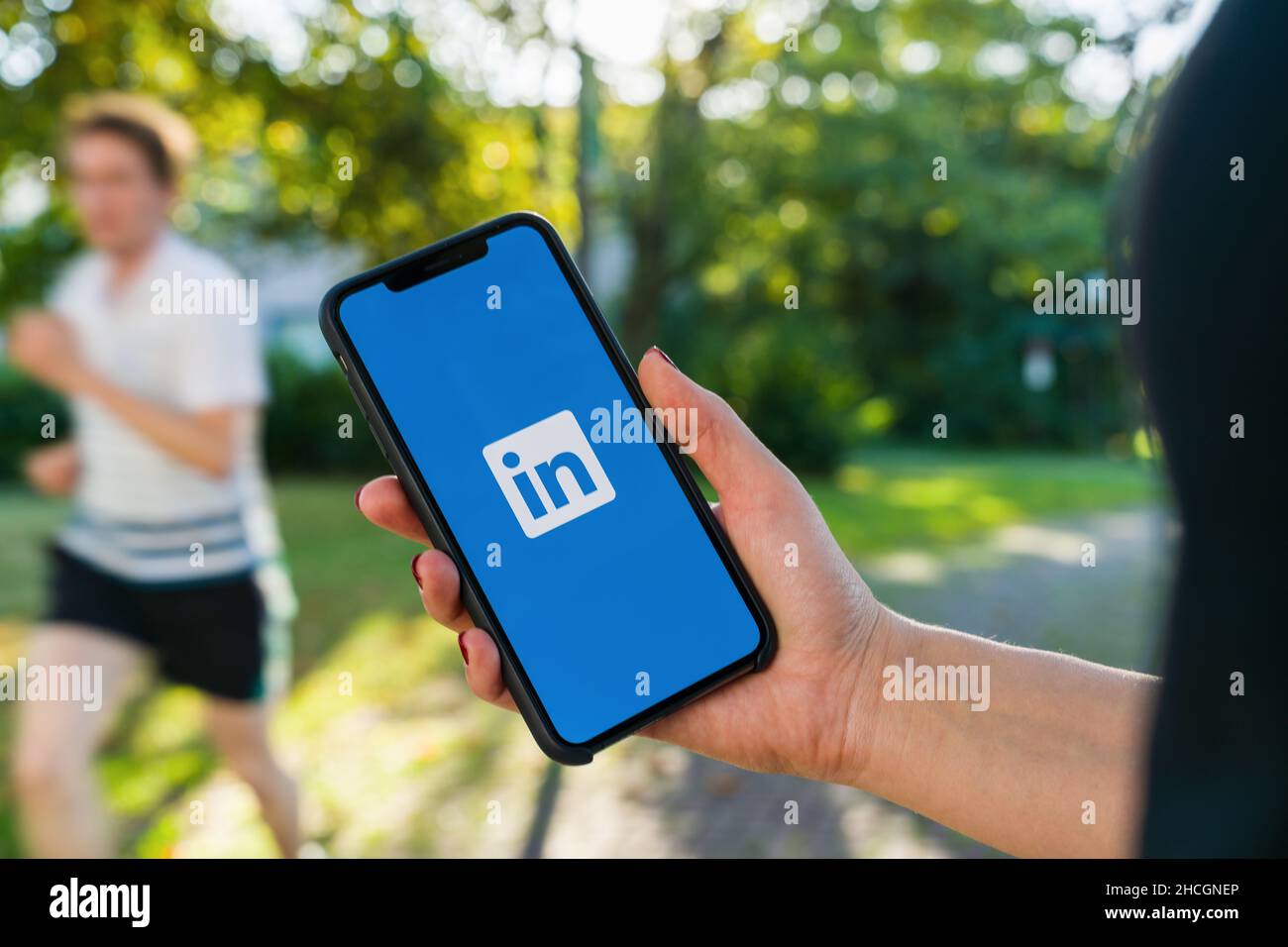 Mano donna che tiene gli iphone X con il logo dell'applicazione LinkedIn sullo schermo. LinkedIn è un servizio di social networking orientato alle aziende. Foto Stock