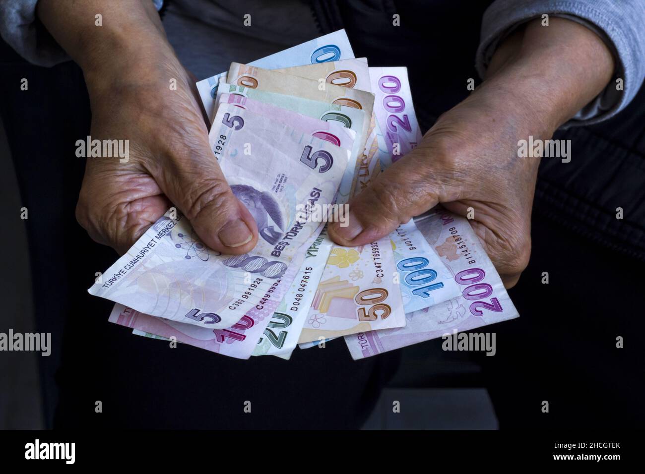 Mani di vecchia persona è in possesso di alcune banconote turche su black shirt.Close up preso, pensione concetto Foto Stock