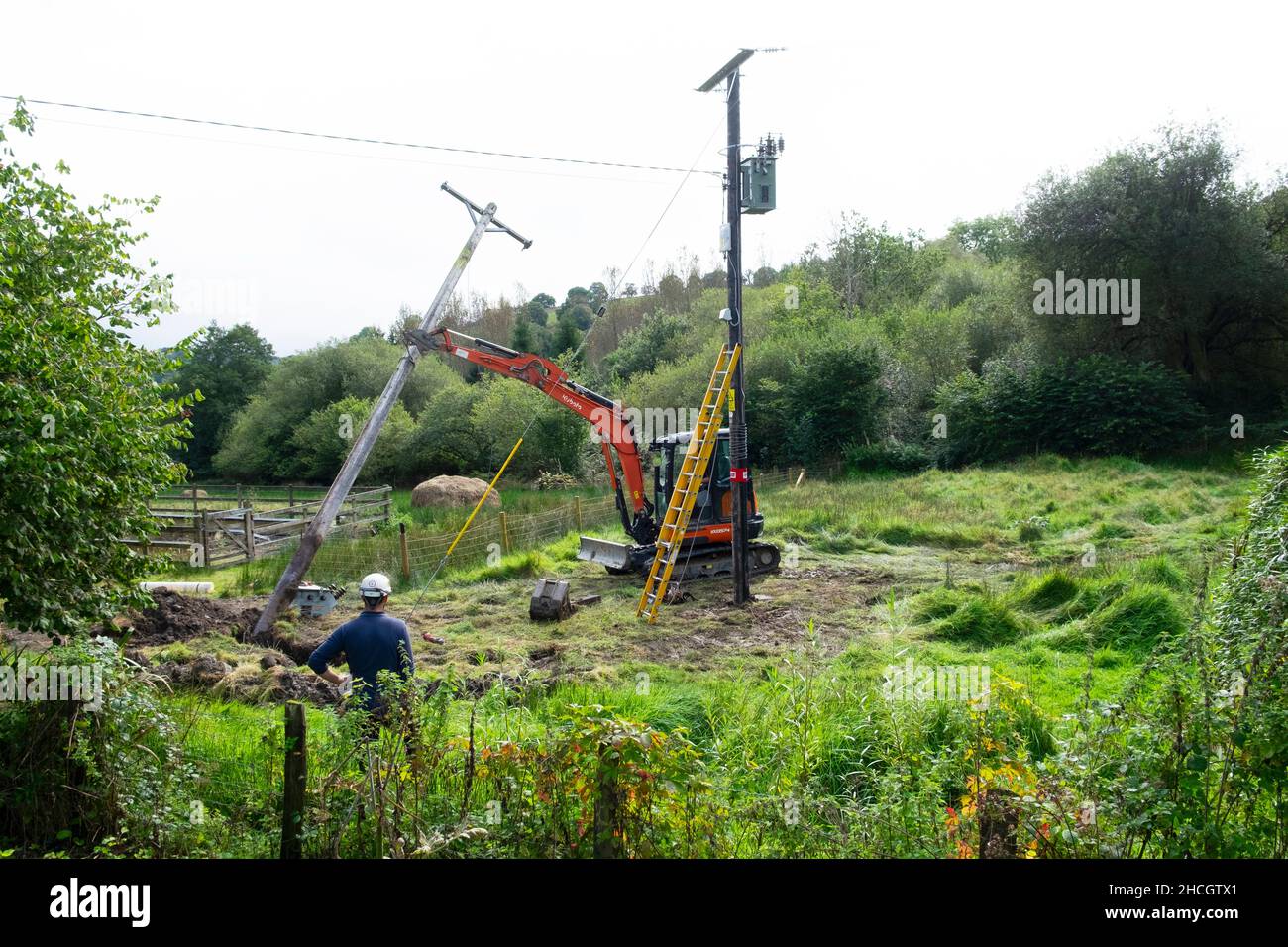 Ingegneri elettrici che lavorano con attrezzature e digger mettere in su linee di pali estate Carmarthenshire Galles Regno Unito 2021 Gran Bretagna KATHY DEWITT Foto Stock