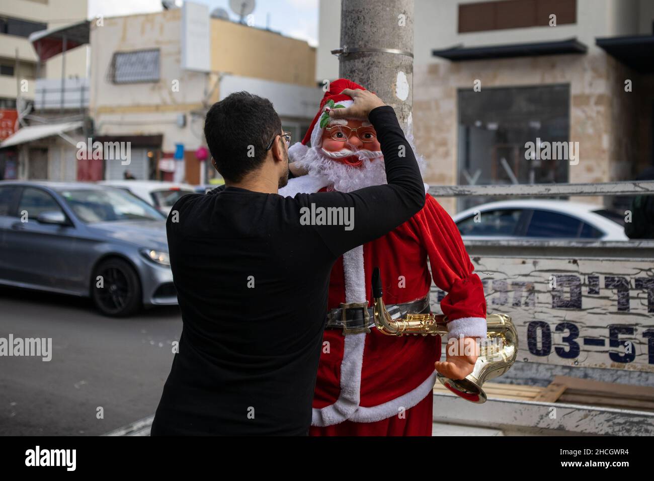 Un negoziante mette una testa su una bambola di Babbo Natale a Jaffa, Tel Aviv, Israele Foto Stock