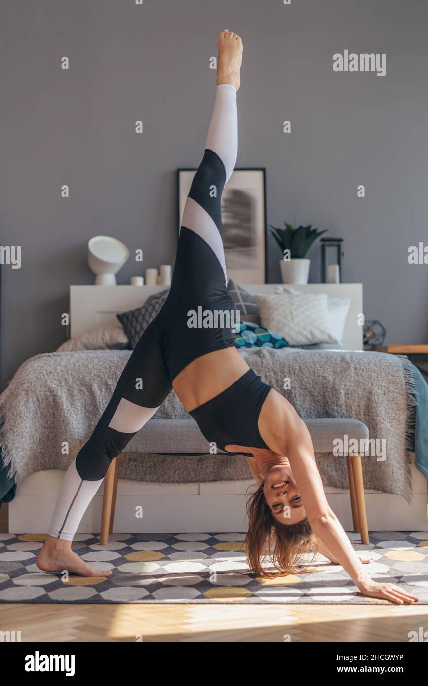 Adatta donna stretching facendo esercizio di yoga. Posa del cane a tre zampe Foto Stock