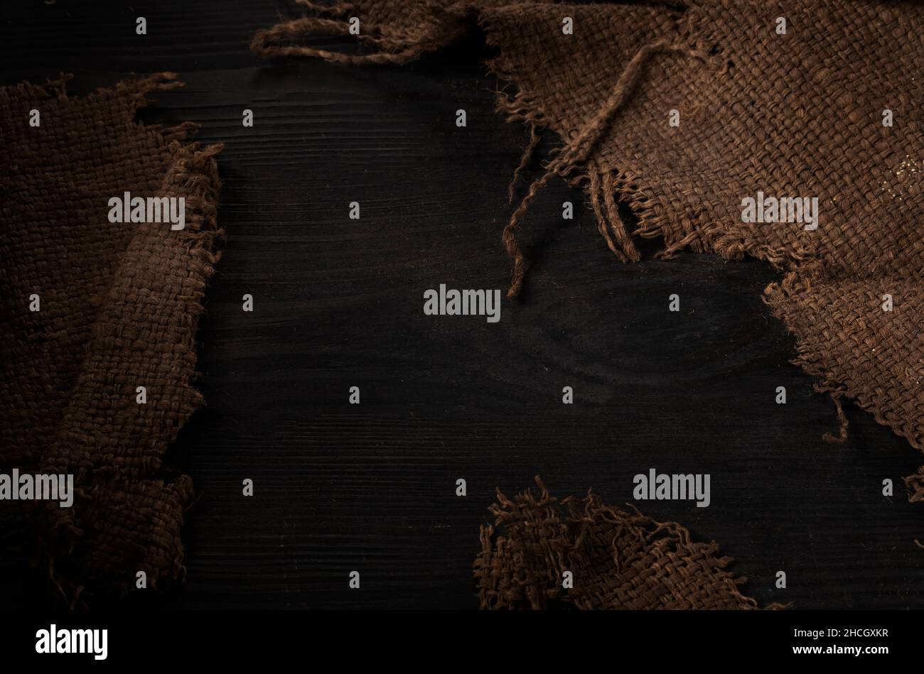 Primo piano di sovrapposizione. Tela ruvida. Tessuto di tessitura ruvido su sfondo di legno. Foto Stock