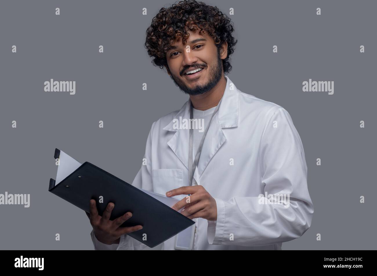 Medico allegro con documenti in mano guardando avanti Foto Stock