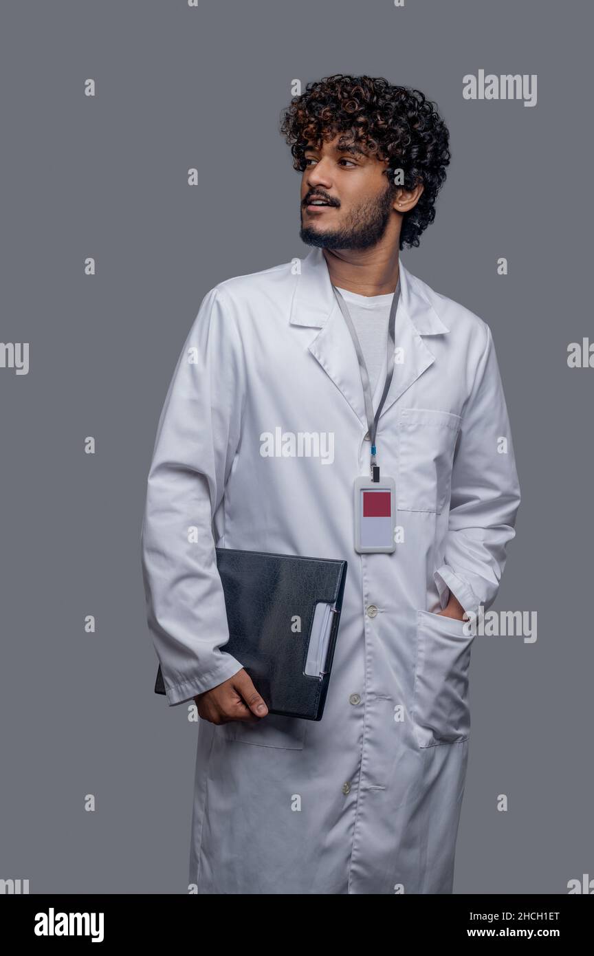 Medico con una cartella di file in mano guardando lontano Foto Stock