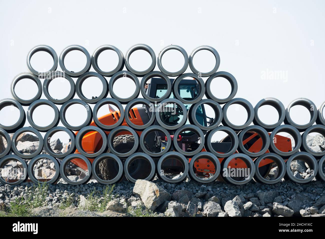 Rullo di strada dietro tubi di cemento impilamento in un cantiere Foto Stock